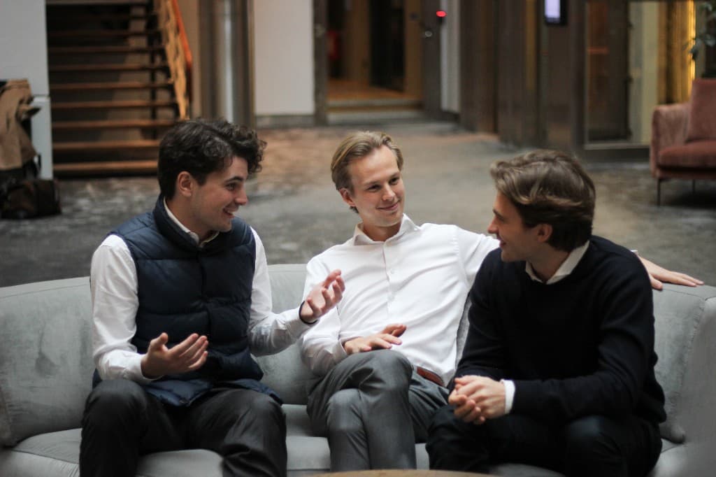 Three Accumeo team members sitting on a sofa, talking in a bright office space